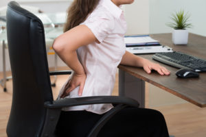 Young Businesswoman On Chair Having Backpain In Office